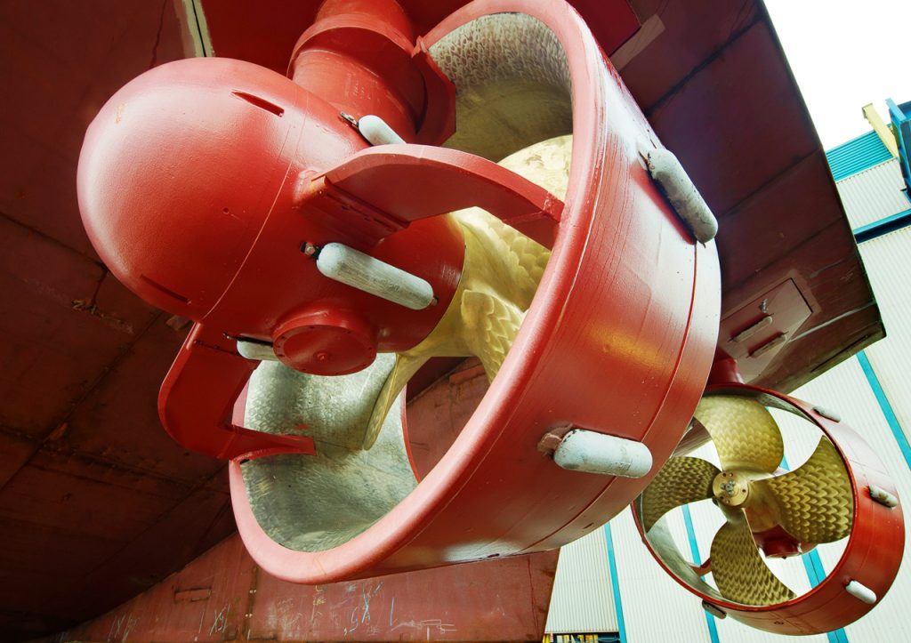 Industrial ship propeller with large blades and red cover, suited for heavy-duty marine vessels, showcasing advanced engineering and durability.