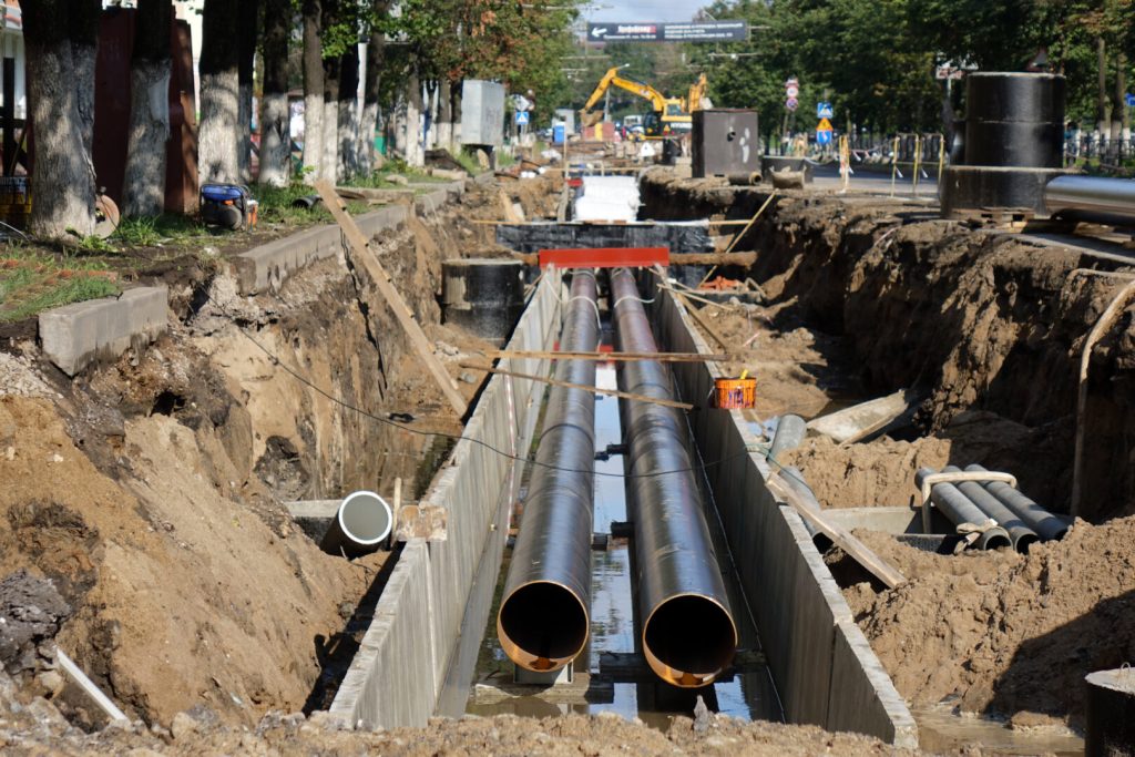 Underground pipeline installation for utilities like water or gas lines, featuring large pipes and construction equipment.
