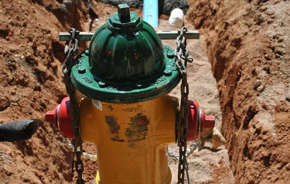 Fire hydrant in a construction site with chains for safety and access.